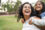 A young mother carries her toddler daughter on her back, both are smiling happily